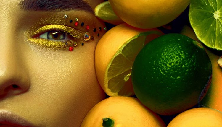 Model lies among many citrus fruits.
