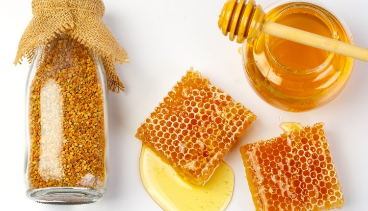 Honeycomb with jar and honey dipper isolated on white background