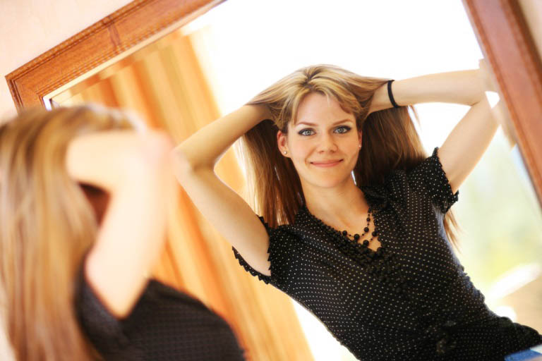 Beautiful young woman looking in the mirror