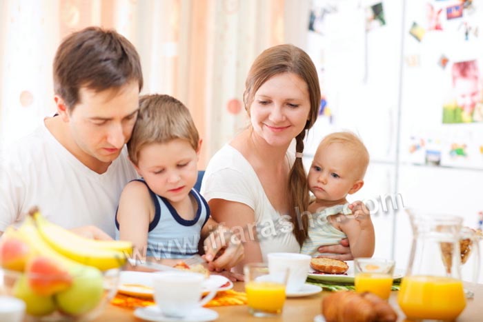 Young happy family with two kids having breakfast together
