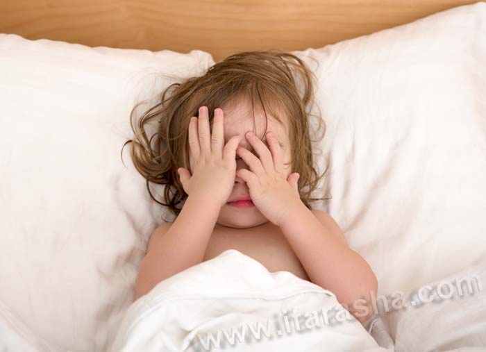 Toddler Girl closing her eyes in the bed, perhaps she is seeing bad dreams.