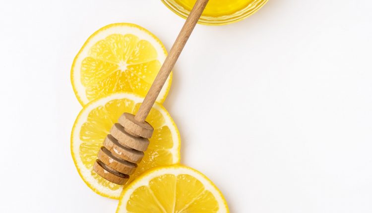 Slace of Fresh Ripe Lemon and Wooden Honey Dipper on White Background Honey Vertical Top View