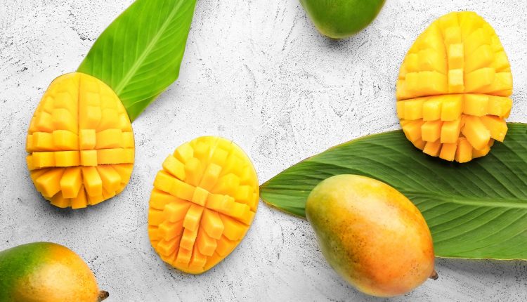 Sweet ripe mangoes on light background